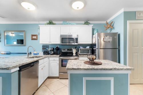a kitchen with white cabinets and a stainless steel refrigerator at Grand Caribbean 115 by Vacation Homes Collection in Orange Beach
