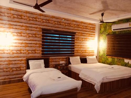 KADAMBINI JUNGLE RESORT في لاتاغري: سريرين في غرفة مع جدار من الطوب
