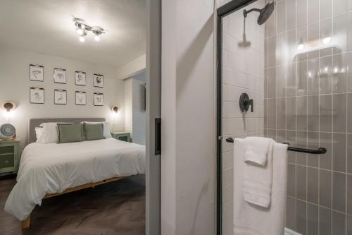 a bedroom with a bed and a glass shower at The Local Motel & Shops in Eugene