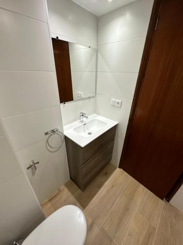 ein Badezimmer mit einem weißen Waschbecken und einem WC in der Unterkunft Apartamento Playa Panadeira in Sanxenxo