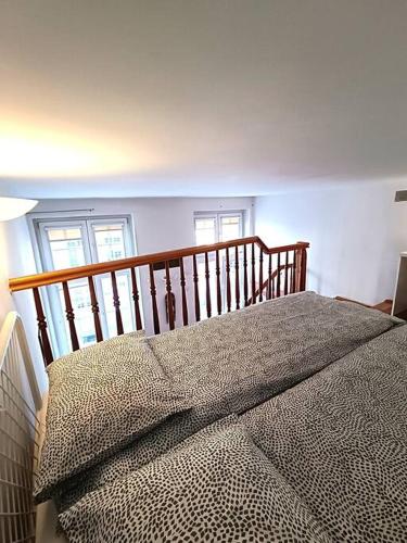 1 dormitorio con 1 cama y una escalera con ventanas en Old Town Mezzanine Apartment, en Gdansk