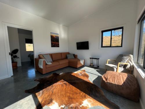 a living room with a couch and a table at Hygge Eco Cabins in Jindabyne