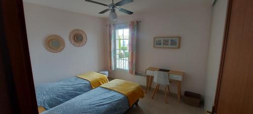 2 Betten in einem Zimmer mit einem Schreibtisch und einem Fenster in der Unterkunft Cosy marina moderne et spacieuse in Aigues-Mortes