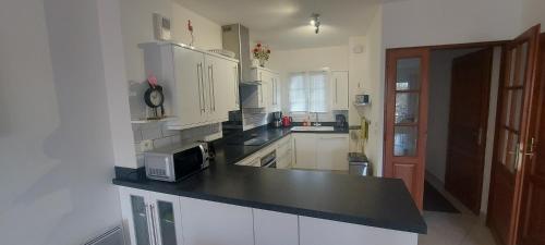 une cuisine avec des armoires blanches et un comptoir noir dans l'établissement Cosy marina moderne et spacieuse, à Aigues-Mortes