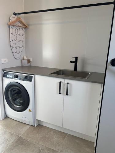 a kitchen with a sink and a washing machine at Hygge Eco Cabins Beautiful New Cabins with Amazing Views in Jindabyne