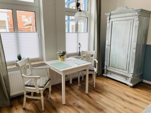a white table and chairs in a room with windows at Aparthotel Domizil in Borkum