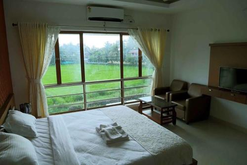 ein Schlafzimmer mit einem Bett und einem großen Fenster in der Unterkunft Captains Cabin backwater resort in Alappuzha