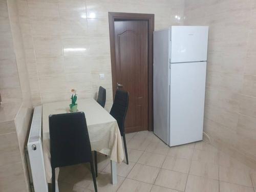 een keuken met een tafel en een witte koelkast bij Casa cu Nuc in Bordeiu