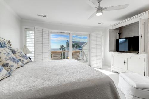 a bedroom with a bed and a tv and a balcony at 62 Beach Club Villa in Isle of Palms