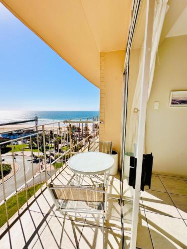 een balkon met een tafel en stoelen en het strand bij Nomacurvy beach front accommodation in Durban