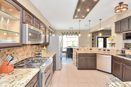 a large kitchen with brown cabinets and a counter top at Tropical Escape Pool Jacuzzi Bar in Alvin TX in Alvin
