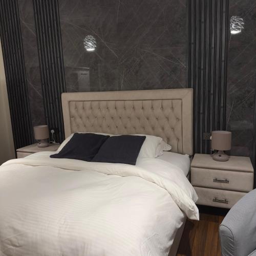 - une chambre dotée d'un grand lit avec des draps et des oreillers blancs dans l'établissement Elegance, à Firq