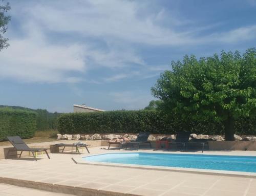 une piscine avec des chaises, une table et un arbre dans l'établissement Mas Cévenol et piscine 8 personnes 4 chambres, à Durfort-et-Saint-Martin-de-Sossenac