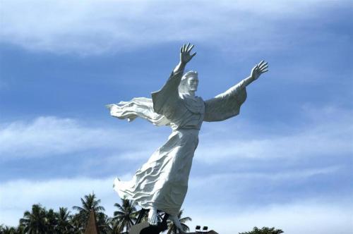 OYO 93168 Permata Ria Hotel في مانادو: تمثال لامرأة بذراعيها في الهواء