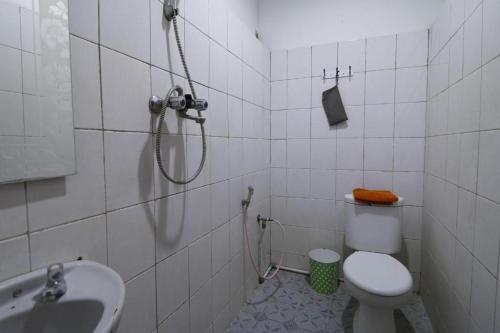 ein Bad mit einer Dusche, einem WC und einem Waschbecken in der Unterkunft OYO 93168 Permata Ria Hotel in Manado