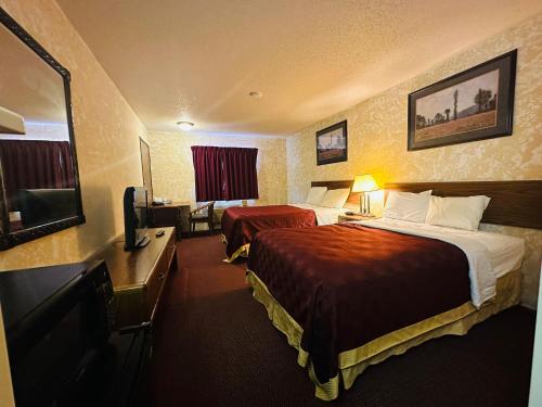 Habitación de hotel con 2 camas, escritorio y TV. en Studio 7 on Main, en West Fargo