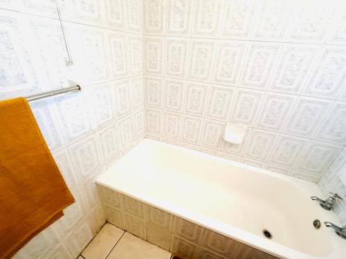 a white bath tub in a bathroom with white tiles at Nomacurvy beach front accommodation in Durban