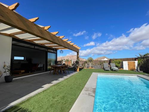 um quintal com uma piscina e uma pérgola em Bungalow + Piscina independiente em La Oliva