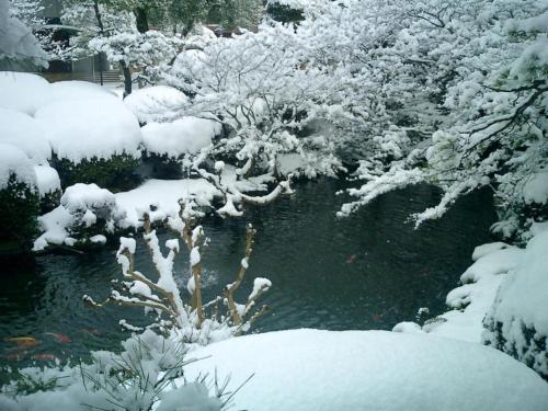 a snow covered garden with a pond and trees at Suikoyen Hotel - Vacation STAY 53816v in Kurume