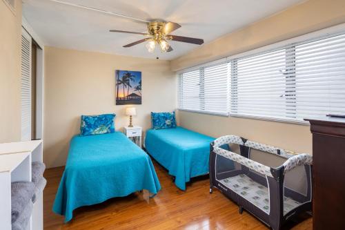 a bedroom with two blue beds and a ceiling fan at Royal Aloha Waikiki Beach in Honolulu