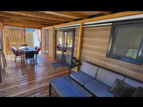 un porche cubierto con sofá y mesa en Mobile home JOY, en Biograd na Moru