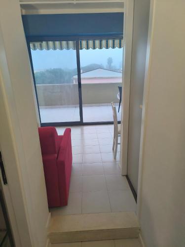 a view of a room with a red chair and a window at Sul Mare con Posto Auto e Terrazzo in Marcelli