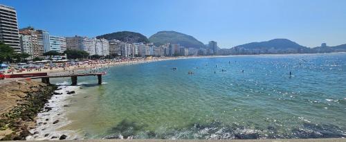 a beach with a pier and people in the water at Copacabana Vibes Studios in Rio de Janeiro