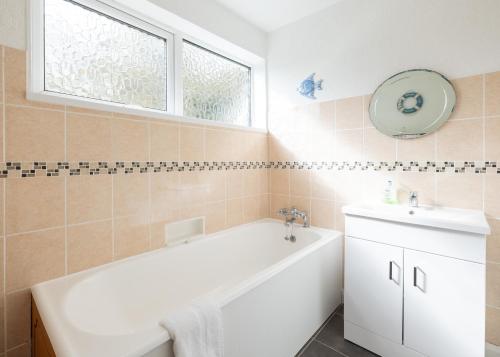 a bathroom with a white tub and a sink at Beach Haven in Wadebridge