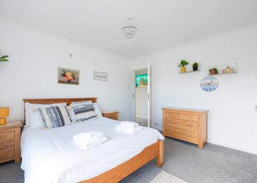 Schlafzimmer mit einem Bett mit weißer Bettwäsche und Holzmöbeln in der Unterkunft Beach Haven in Wadebridge