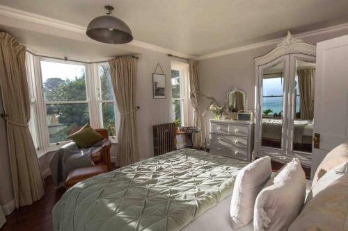 1 dormitorio con 1 cama, vestidor y ventanas en Family House with Garden & Sea Views, en Mousehole