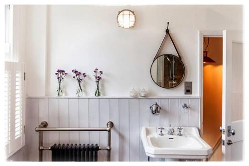 baño con lavabo y jarrones de flores en un estante en Family House with Garden & Sea Views, en Mousehole