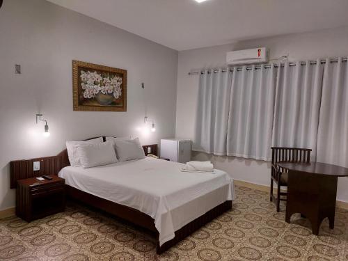 a hotel room with a bed and a table and a desk at Hotel Presidente in Imperatriz
