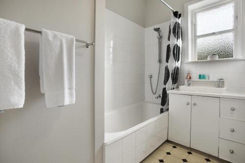 a white bathroom with a tub and a sink at Prosper Point Home with BBQ, Patio and Parking in Auckland