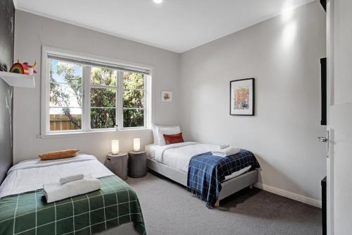 a bedroom with two beds and a window at Prosper Point Home with BBQ, Patio and Parking in Auckland