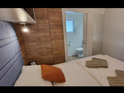 a bedroom with a bed with an orange pillow on it at Mobile home JOY in Biograd na Moru