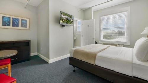 a bedroom with a bed and a desk and a television at Crystal Bay Historic Hotel in St Petersburg