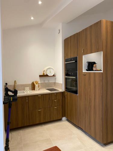 une cuisine avec des armoires en bois et une horloge au mur dans l'établissement Superbe T2 au cœur de la Ciotat, à La Ciotat