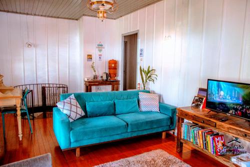 a living room with a blue couch and a tv at Gramado Guest House in Gramado