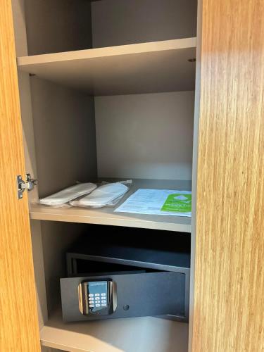 a cupboard with a drawer with a phone in it at New Wave Apart-Hotel in Batumi