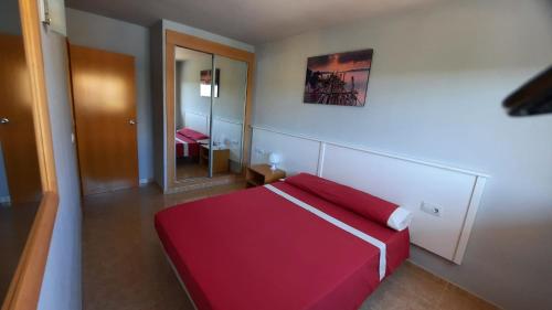 Schlafzimmer mit einem roten Bett und einem Spiegel in der Unterkunft Enjoy the swimming pool and relax in Cap Salou in Salou