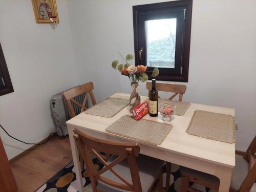 a table with a bottle of wine and flowers on it at Kojadinovica Koliba in Mokra Gora