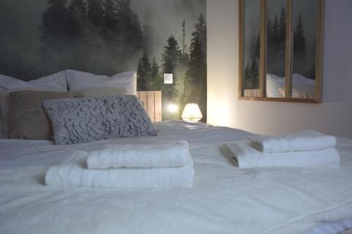 a white bed with white sheets and pillows on it at Domaine des cyprès in Vaudrimesnil