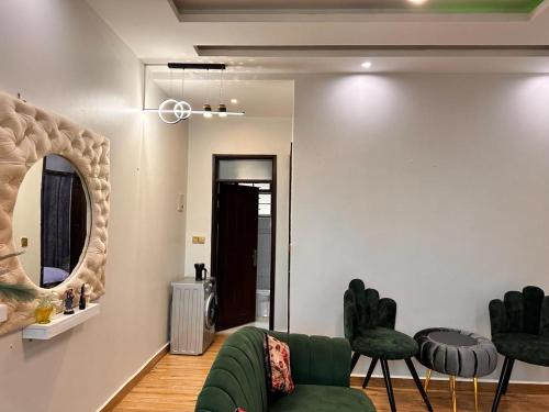 a living room with a green couch and a mirror at Lyrrh Homes Apartments in Kira
