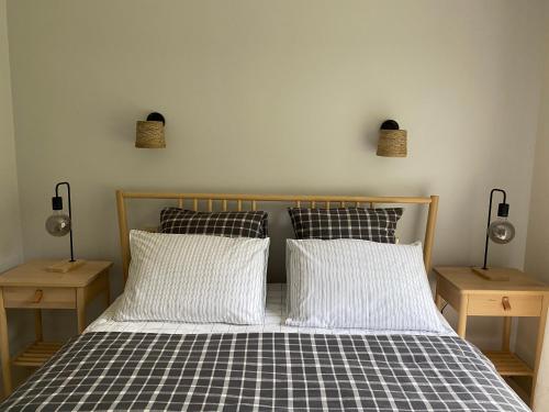 1 cama con 2 almohadas y 2 luces en la pared en logement avec accès piscine, en Chaumont-sur-Tharonne