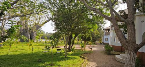 un giardino con alberi, un edificio e un prato di Sita Joyeh Baobab Island Hotel a Kuloro