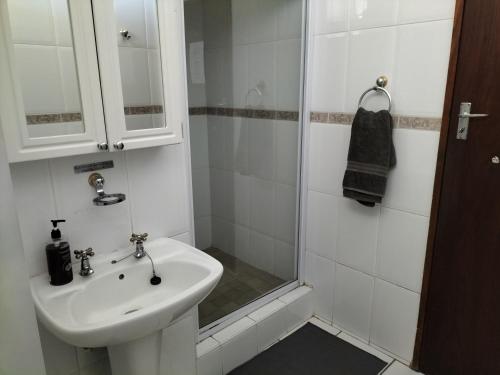 a white bathroom with a sink and a shower at Fair Haven in Bloemfontein