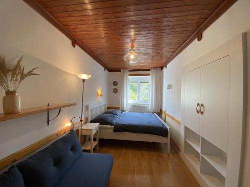 a bedroom with a bed and a couch and a window at Pension Hamry in Vranov nad Dyjí