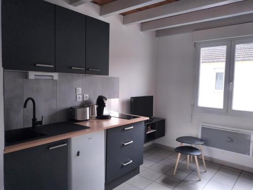 une cuisine avec des armoires noires, un évier et un tabouret dans l'établissement Les Chauvets, à Langogne
