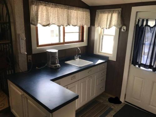 cocina con encimera y fregadero y 2 ventanas en Bristol Cottage- Coachlite Resort in Minocqua, en Minocqua