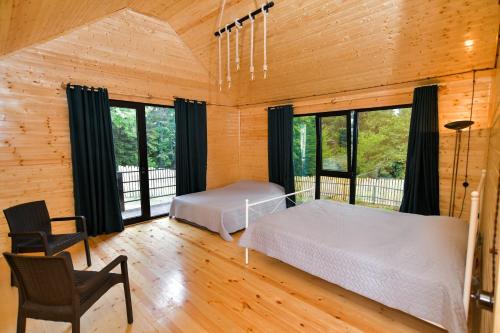 um quarto com 2 camas num quarto com janelas em Cottage Mebirashi em Ambrolauri